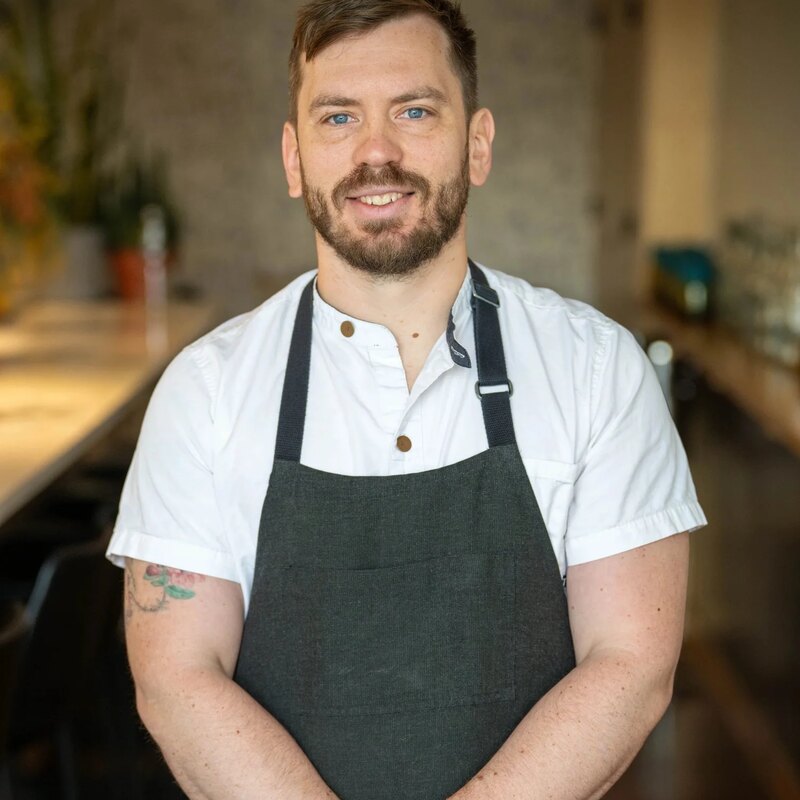 Cameron Rolka, chef at Umbo, in a dark apron at the bar